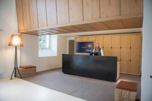 un homme debout à un bureau dans une pièce avec une télévision dans l'établissement Fontevraud L'Ermitage, à Fontevraud-l'Abbaye