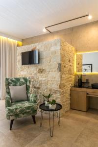 a living room with a green chair and a tv on a stone wall at Kalamaki Luxury Suites in Kalamaki