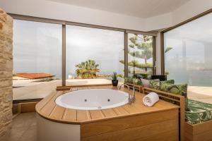 ein Badezimmer mit einer großen Badewanne vor einem großen Fenster in der Unterkunft Kalamaki Luxury Suites in Kalamaki + 43 Fotos