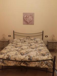 a bed in a bedroom with a heart on the wall at Casa Francesca La Valle di Erice in Valderice