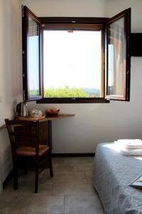 Cette chambre comprend une table, une fenêtre et un lit. dans l'établissement Agriturismo La Lupa, à Madonna della Provvidenza