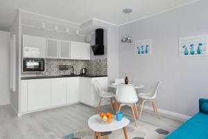 una cucina con armadi bianchi, tavolo e sedie di Luxury Apartment Solvo a Danzica