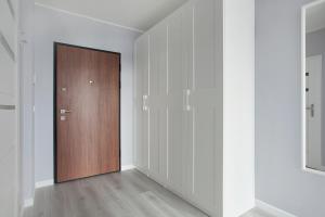 a hallway with a wooden door and white walls at Luxury Apartment Solvo in Gdańsk +13 photos