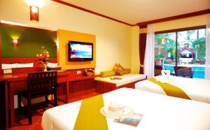 a hotel room with two beds and a desk and a television at Fanari Khaolak Resort - Courtyard SHA Extra Plus in Khao Lak