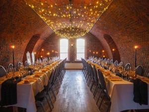 Oscarsborg Castle Hotel & Resort في دروباك: غرفة كبيرة فيها طاولات وكراسي طويلة