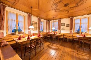 un restaurante con mesas y sillas de madera y ventanas en Landgasthof Rössle - Beim Kräuterwirt en Oberstaufen