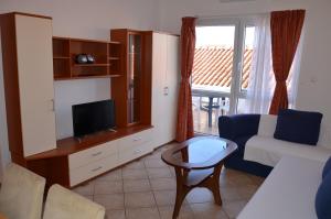 - un salon avec une télévision, un canapé et une table dans l'établissement Apartments Pirovcanka, à Pirovac