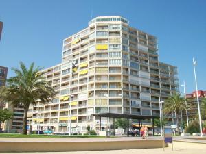 a tall building with palm trees in front of it at Infante - Primera Línea de Playa in Playa de Gandia