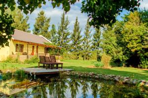 un banc à côté d'un étang en face d'une maison dans l'établissement Rosedale Organic Farm Bed & Breakfast, à Addo