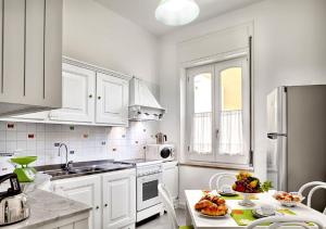 une cuisine avec des placards blancs et une table avec de la nourriture. dans l'établissement Stella House, à SantʼAgata sui Due Golfi