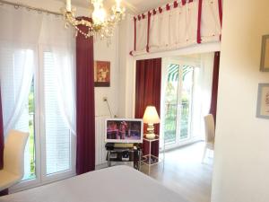 a bedroom with a bed and a tv and some windows at LES GRANDS CEDRES C1 7 Avenue de Fabron in Nice