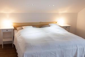 um quarto com uma cama branca com duas mesas de cabeceira em Dorf Alm Ferienwohnung em Schwalmtal