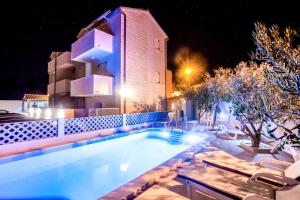 a swimming pool in front of a building at night at Bol apartments Gospojica in Bol