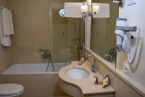 een badkamer met een wastafel, een toilet en een bad bij Torrione Hotel in Reggio di Calabria