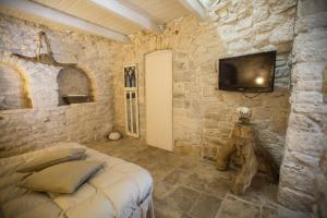 a bedroom with a bed and a tv on a stone wall at IL TRULLO DELLA MASSAIA in Alberobello