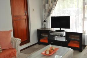 ein Wohnzimmer mit einem TV und einem Teller mit Lebensmitteln auf dem Tisch in der Unterkunft Pelican Place Guest Cottages in Durbanville