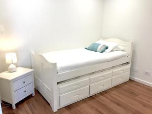 a white bed in a room with a night stand at Kiama Executive in Kiama