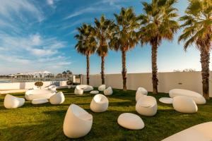 a park with white chairs and palm trees at Hotel Apartamento Dunamar in Monte Gordo