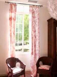 a window with pink curtains and two chairs in a room at Douceur Girondine in Saint-Selve