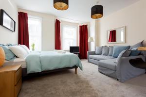 a bedroom with a bed and a couch and red curtains at Stylish Town Centre Apartment Close to Beach and Shops in Bournemouth