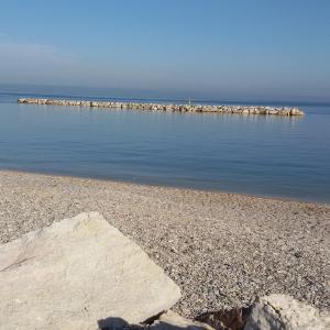 a rocky beach with a pier in the water at B&B A Casa di Mael in San Costanzo