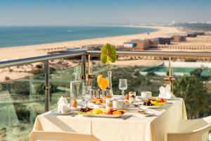 una mesa con comida y vistas a la playa en Hotel Apartamento Dunamar, en Monte Gordo