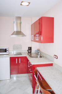 una cocina roja con armarios rojos y fregadero en Vivienda Turistica Arabeluj en Güéjar-Sierra