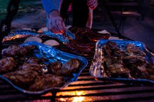 Eine Person kocht Fleisch auf einem Grill in der Unterkunft Dom Wczasowy Mariza DOMKI LETNISKOWE in Czaplinek