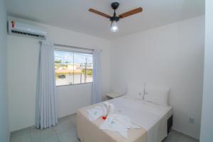 1 dormitorio con 1 cama, ventilador de techo y ventana en Porto Luar, en Porto Seguro