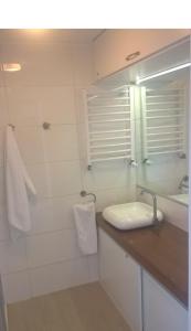 a white bathroom with a sink and a mirror at Apartament pod Czarną Górą in Sienna