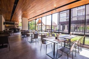 a restaurant with tables and chairs and large windows at Amanta Hotel Nongkhai in Nong Khai
