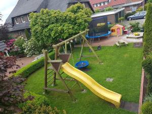 Un parque infantil con un tobogán en un patio en Hausnordlicht Dachspitze, en Dornumergrode