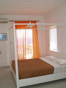 a bedroom with a bed with an orange curtain and a window at Poseidon Seaview Studios in Afitos