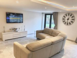 een woonkamer met een bank en een klok aan de muur bij Millstream Mews in Bakewell
