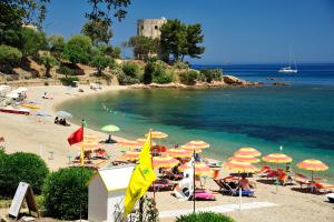 a beach with many umbrellas and people in the water at Hotel Agugliastra in Santa Maria Navarrese