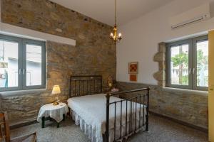 a bedroom with a bed and a stone wall at Iliopetra House in Sívas