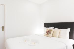 białe łóżko z czarnym zagłówkiem i białymi poduszkami w obiekcie APOSENTUS - Your Home in Martires da Liberdade w Porto