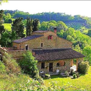 a large stone house on a hill in a field at Casa nel bosco Il Grottone in Montaione