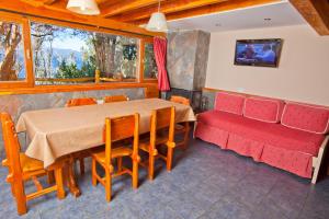 comedor con mesa y sofá rojo en Cabañas Las Marias Del Nahuel en San Carlos de Bariloche