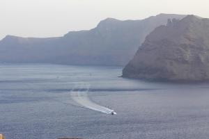 a boat in the water with mountains in the background at White Side Suites in Oia