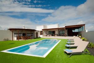 ein Haus mit Pool und Rasen in der Unterkunft Las Caletas Village Playa Blanca in Playa Blanca