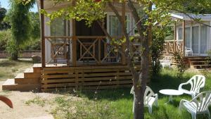 dom z białymi krzesłami, stołem i drzewem w obiekcie Camping Les Castors w Calvi