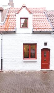 a white house with red windows and a red door at Romantic 16th century workers house in Ghent