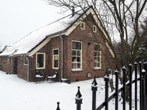 a brick house with a fence in the snow at Lasca in Schoonoord