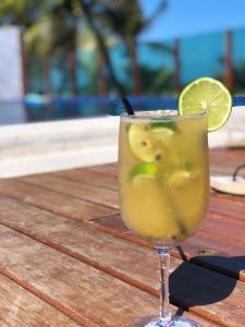 a drink sitting on a wooden table with a slice of lime at Gabrielly Praia Hotel in Guaibim