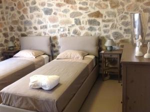 a bedroom with two beds and a stone wall at VILLA ASTERAKI private pool, magic sunsets, near Elafonisi in Ãyios FÃ³tios