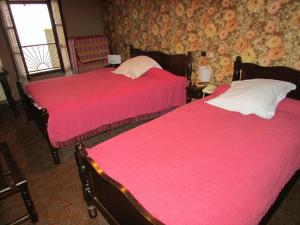 ヴィルフランシュ・ド・ルエルグにあるAuberge de la Posteの赤いシーツが備わるドミトリールームのベッド2台