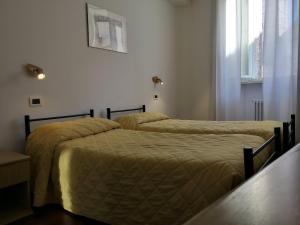 2 Betten in einem weißen Zimmer mit Fenster in der Unterkunft Arco del vento in Assisi