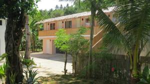 a house with a fence and trees in front of it at Binucot Beach Resort in Ferrol