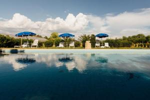 einen Pool mit blauen Sonnenschirmen und Stühlen in der Unterkunft Agriturismo Il Querciolo in Grosseto